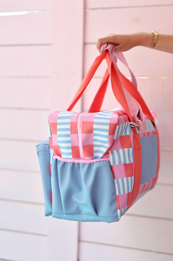 Colorful patterned duffel bag in pink and blue, made from durable material with sturdy handles.