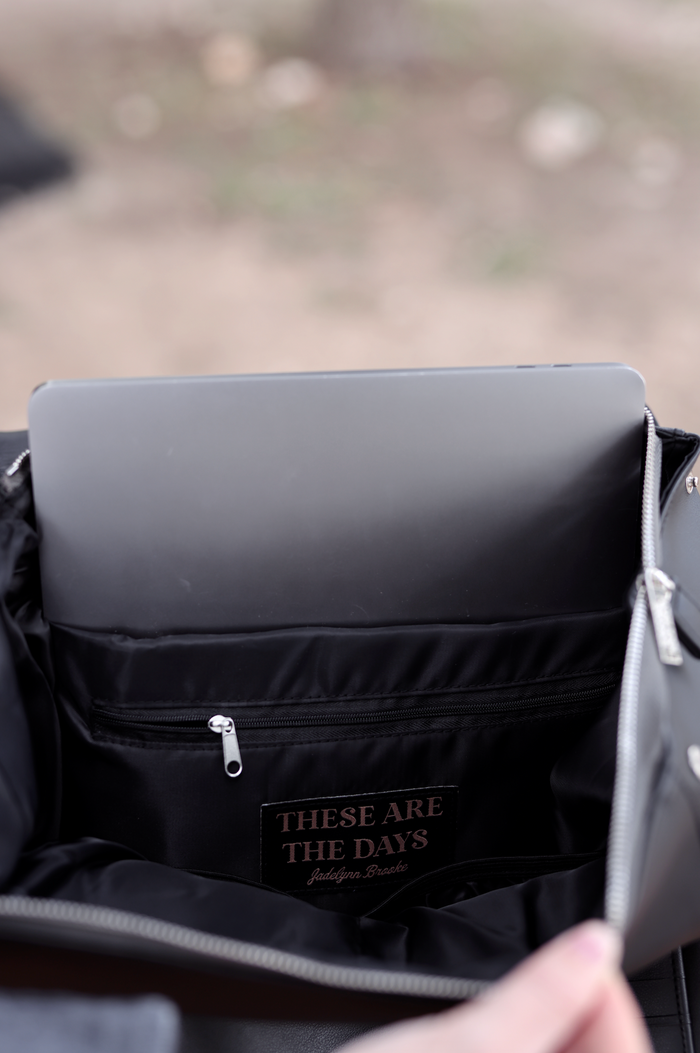 Interior view of a black tote bag, featuring a zip pocket and a spacious compartment for a laptop.