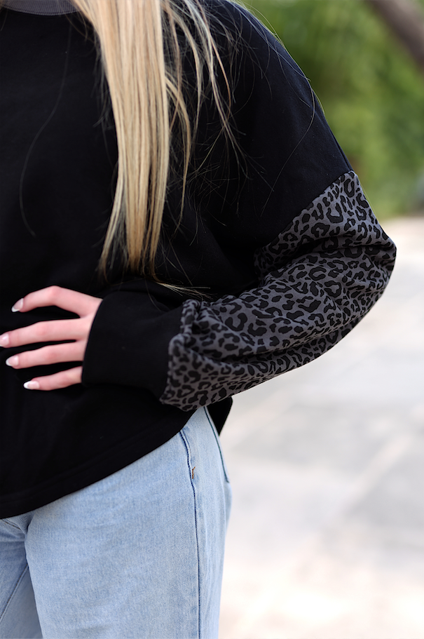 Black sweatshirt with leopard print sleeves, perfect for casual style and comfort.