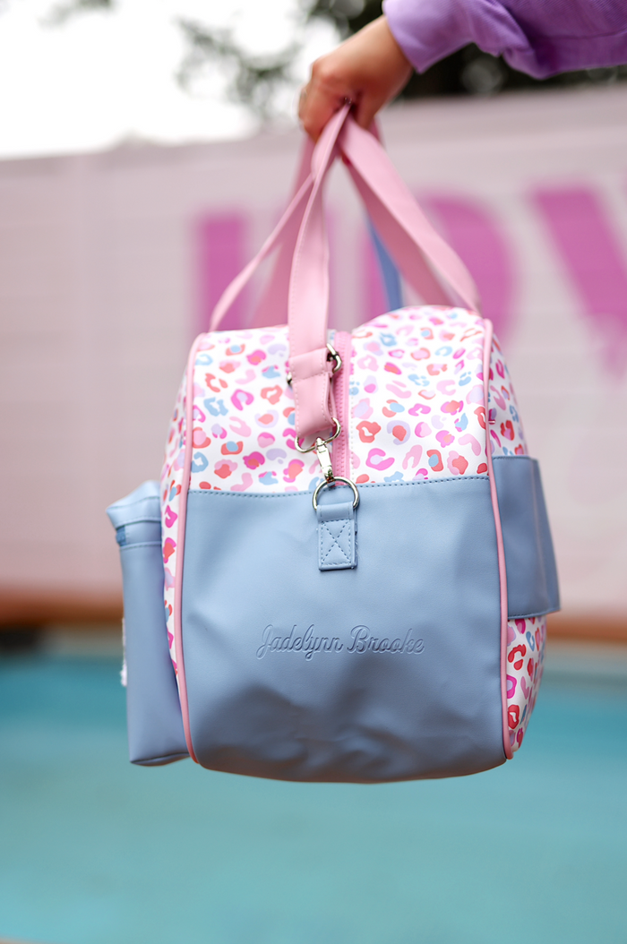 Colorful leopard print tote bag in pink and blue, made of durable materials with a detachable water bottle holder.