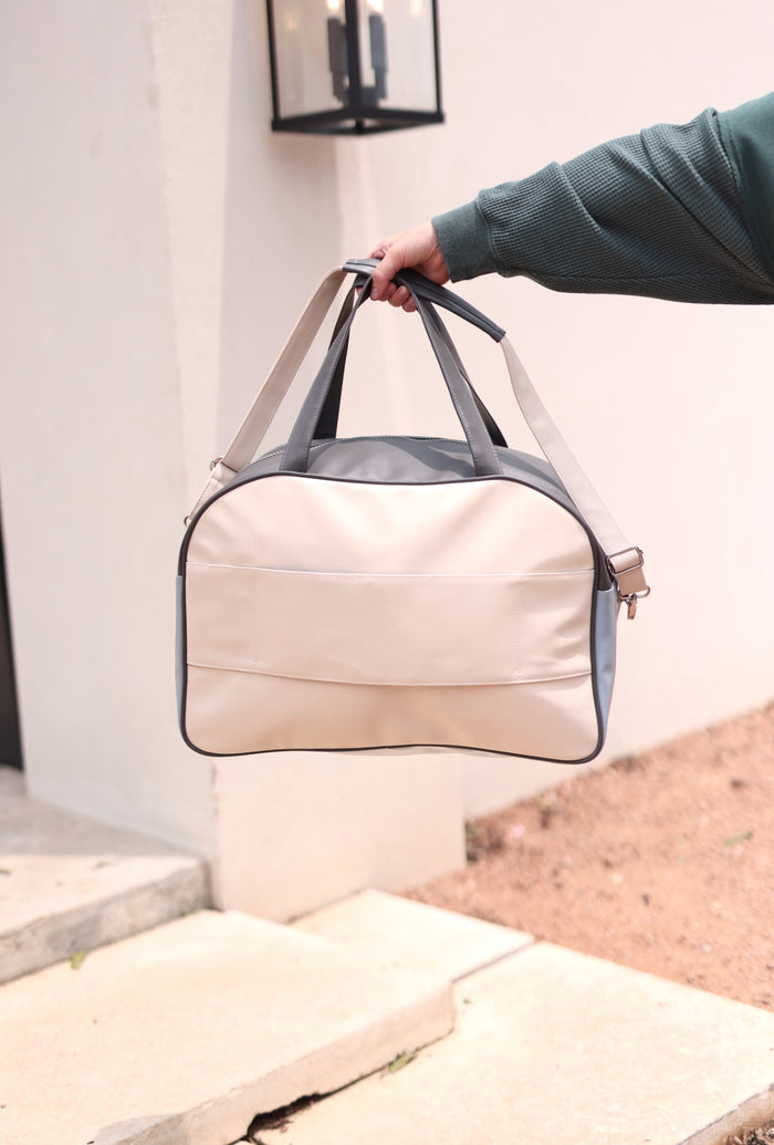 Stylish beige and gray duffel bag, perfect for travel, made from durable materials with comfortable handles.