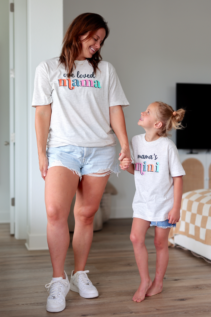 Matching gray t-shirts for mom and daughter, featuring colorful prints 'one loved mama' and 'mama's mini'.