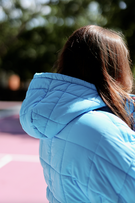 Light blue quilted puffer jacket with a hood, perfect for casual outdoor wear.