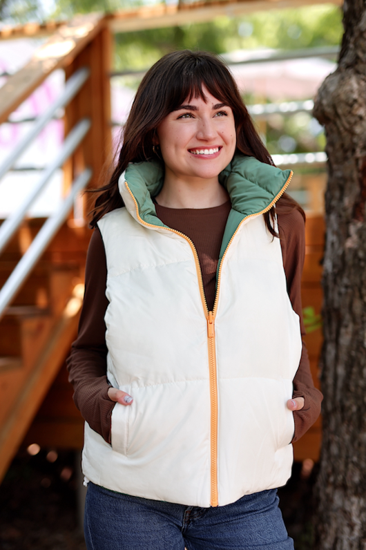 Women’s cream puffer vest with olive green collar, zippered front, and side pockets, perfect for layering.