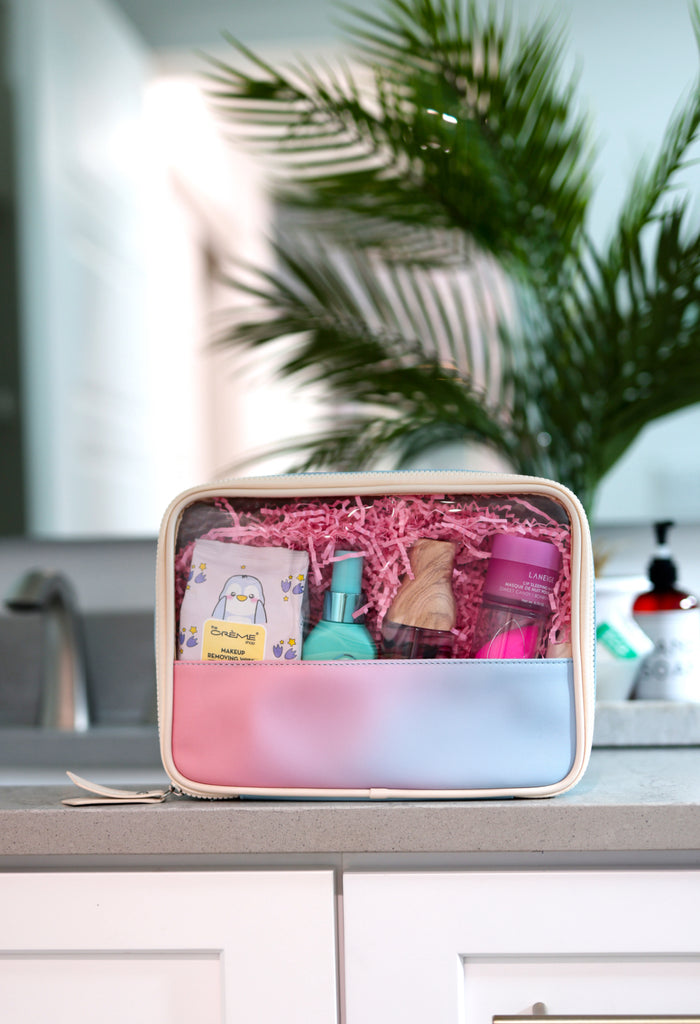 Pastel gradient makeup bag with beauty products, including cleanser, toner, and makeup remover wipes.