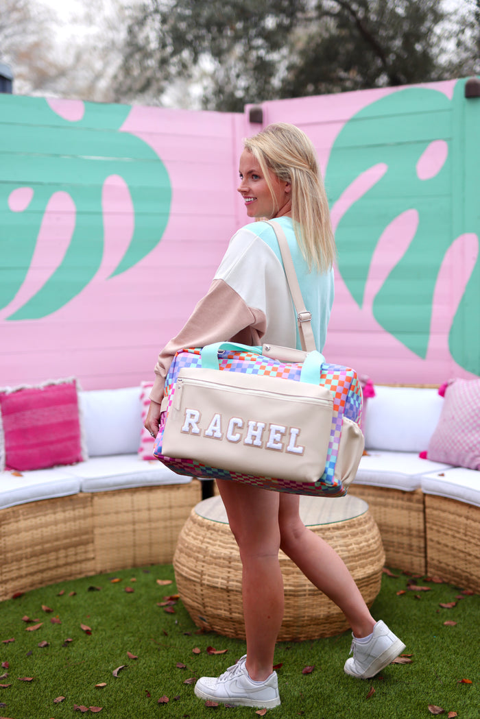 Colorful personalized duffel bag in pastel shades, featuring padded handles and stylish design.