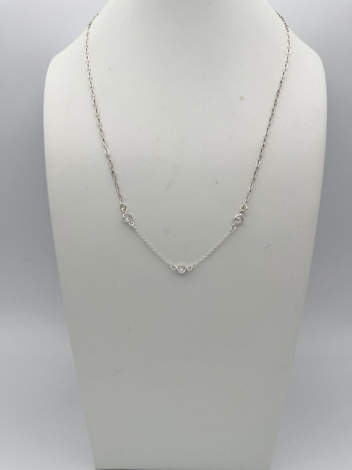 Delicate silver chain necklace with bezel-set clear stones displayed on white jewelry bust