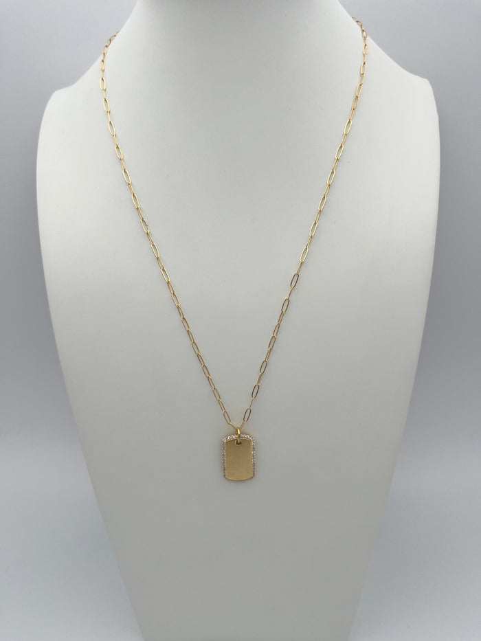 Gold-toned necklace with oval link chain and rectangular pendant with textured border displayed on white jewelry bust