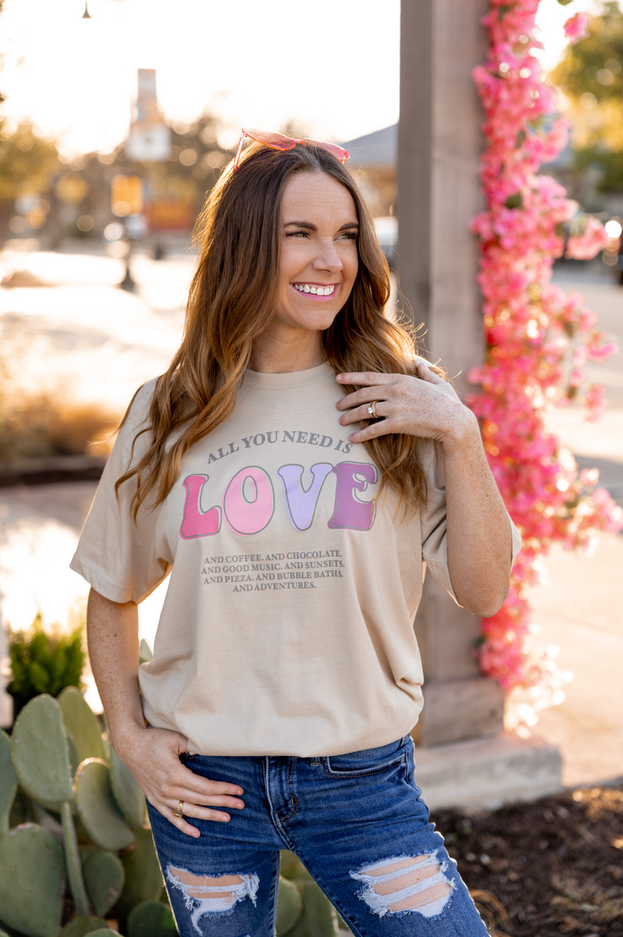 Beige graphic t-shirt with 'All You Need is Love' text, casual style, perfect for everyday wear.