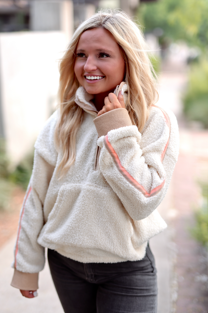 Soft cream fleece pullover with pink accents, half-zip design, perfect for casual wear.