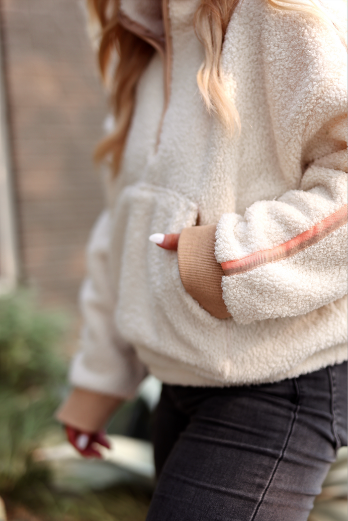 Cozy cream fleece pullover with contrasting sleeve detail and front pocket, perfect for chilly weather.