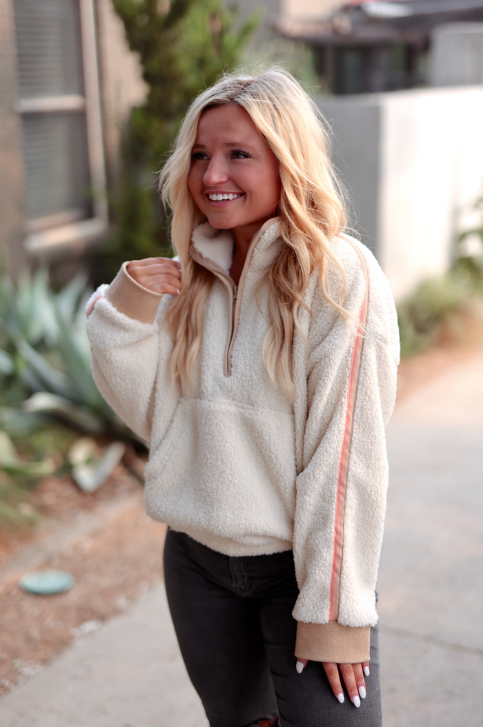 Cream fleece half-zip pullover with pink stripe detail, perfect for cozy casual wear.