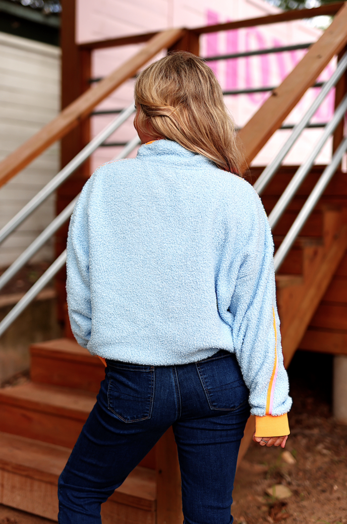 Cozy blue fleece pullover with orange striped cuffs, perfect for casual wear or lounging.