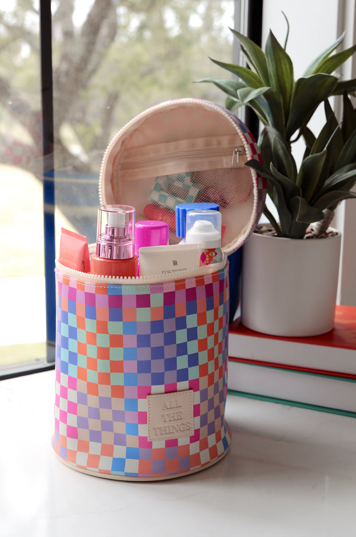 Colorful checkered cosmetic bag with various beauty products inside, perfect for travel.