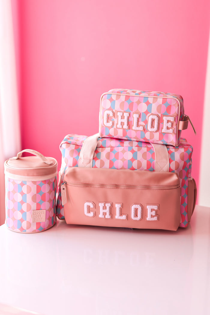 Chloe patterned bag set in pink, featuring spacious duffel, zip pouch, and round container for stylish storage.