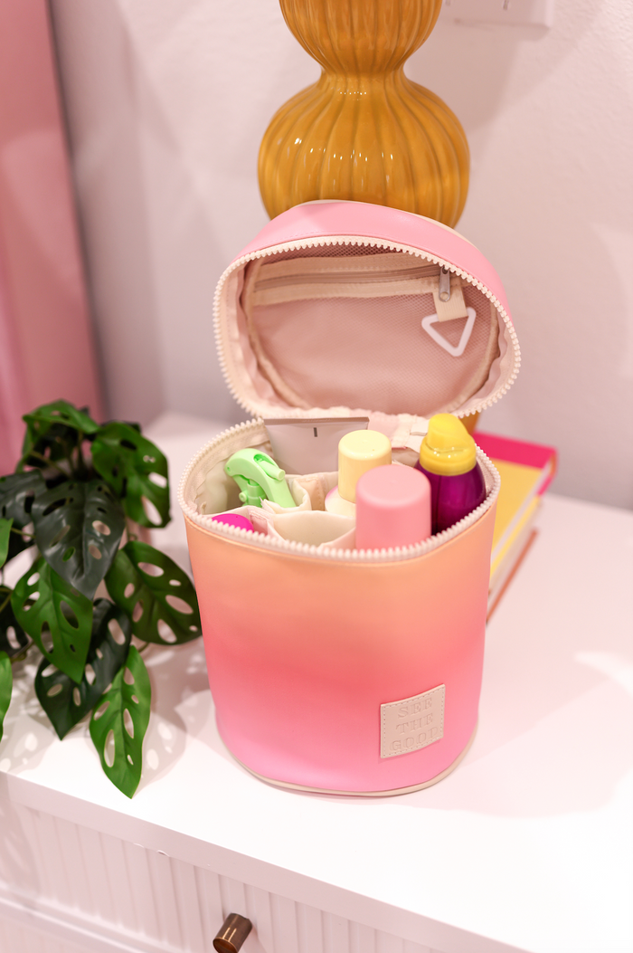 Colorful pink gradient makeup bag with zipper, featuring organized compartments for beauty products.