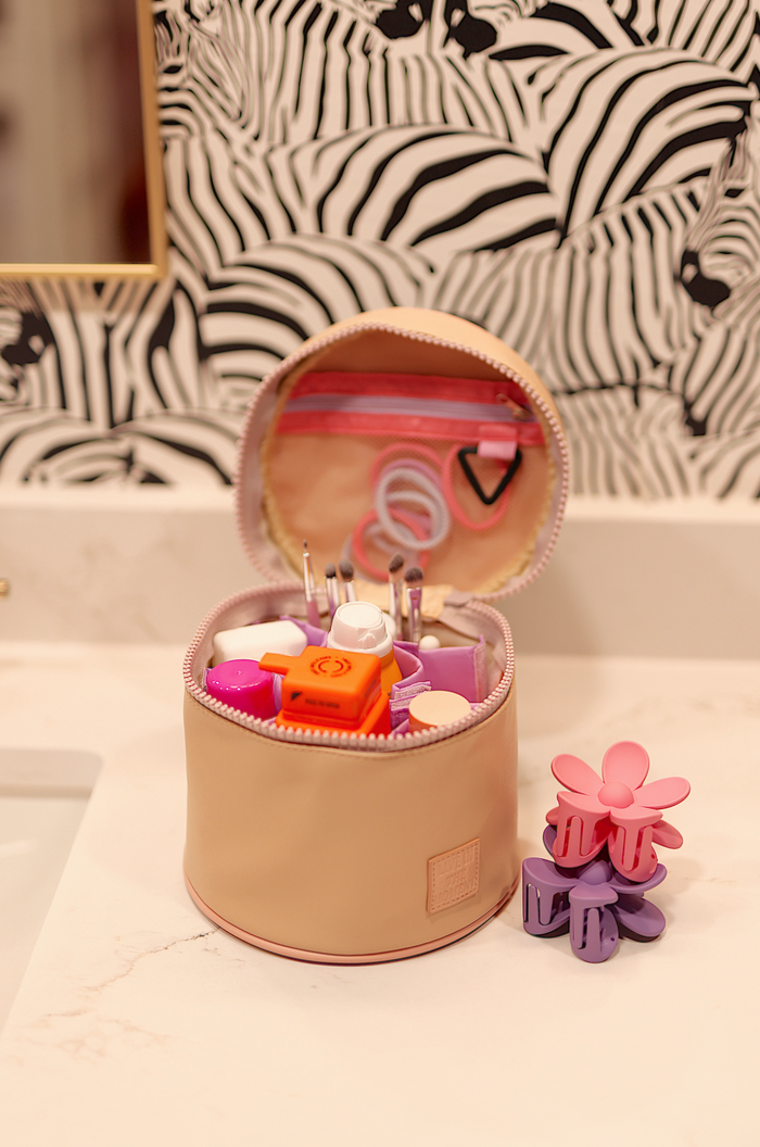 Peach round makeup organizer with various beauty tools and colorful hair clips.