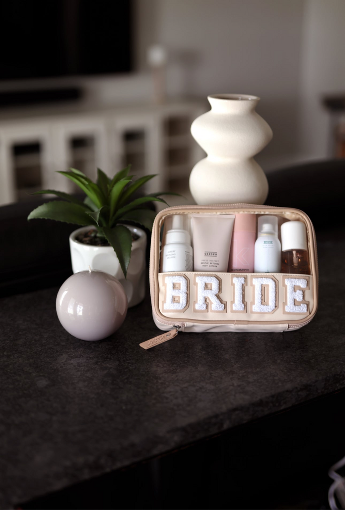 Makeup set with 'BRIDE' on a dark surface with decorative items.