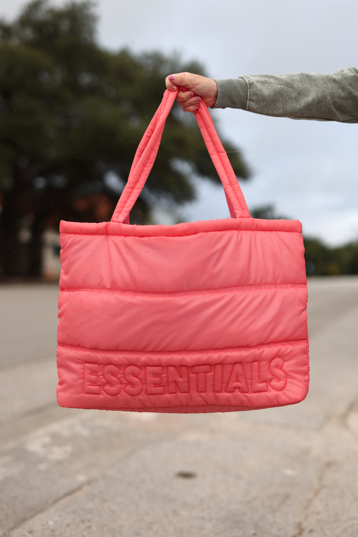 Stylish pink quilted tote bag with embossed 'ESSENTIALS' logo, perfect for everyday use.