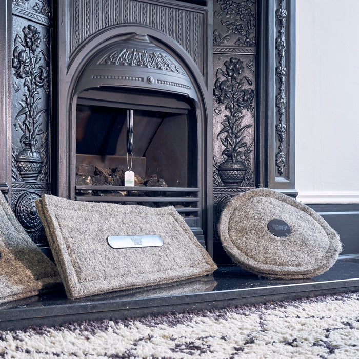 Two wool chimney blockers standing in front of a fireplace with an inserted Chimney Sheep.