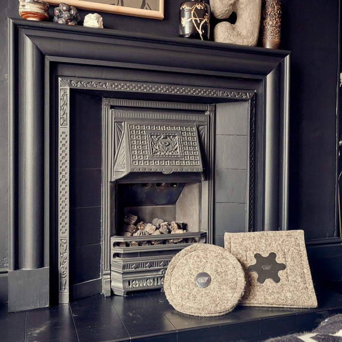 One round and one square Chimney Sheep standing up in front of a fireplace.
