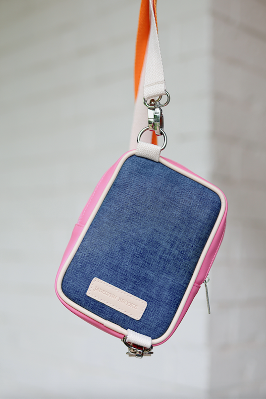 Stylish denim crossbody bag with pink accents and adjustable strap, perfect for outdoor adventures.
