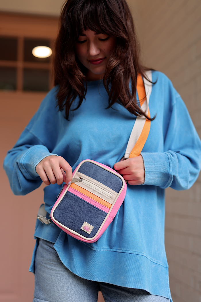Colorful crossbody bag with pink accents, denim material, and adjustable strap, perfect for casual outings.
