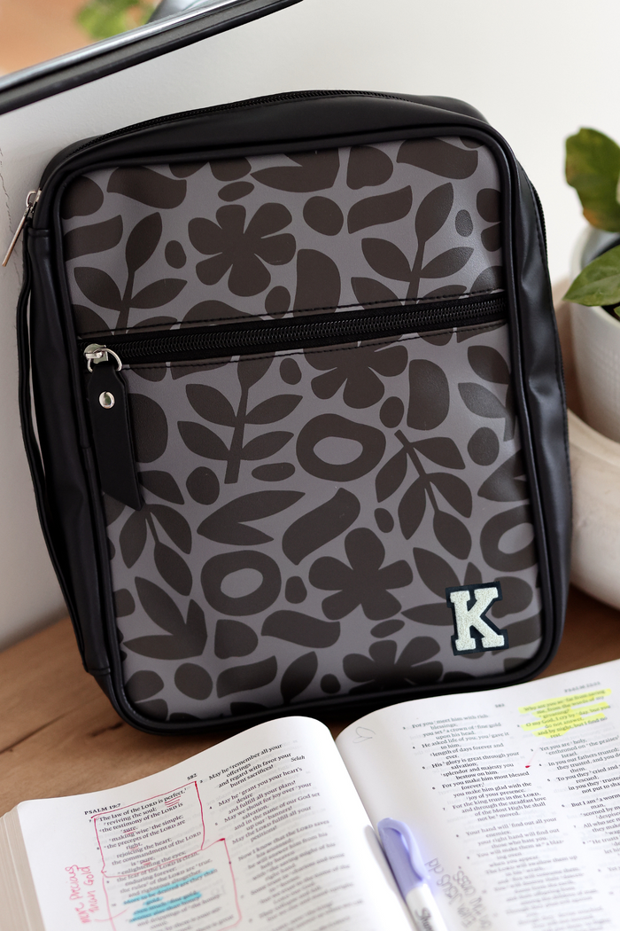 Stylish gray floral print backpack with zipper, featuring an embroidered letter K.