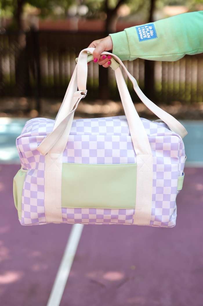 Stylish purple checkered duffel bag with mint green accents and sturdy handles, perfect for travel or gym.