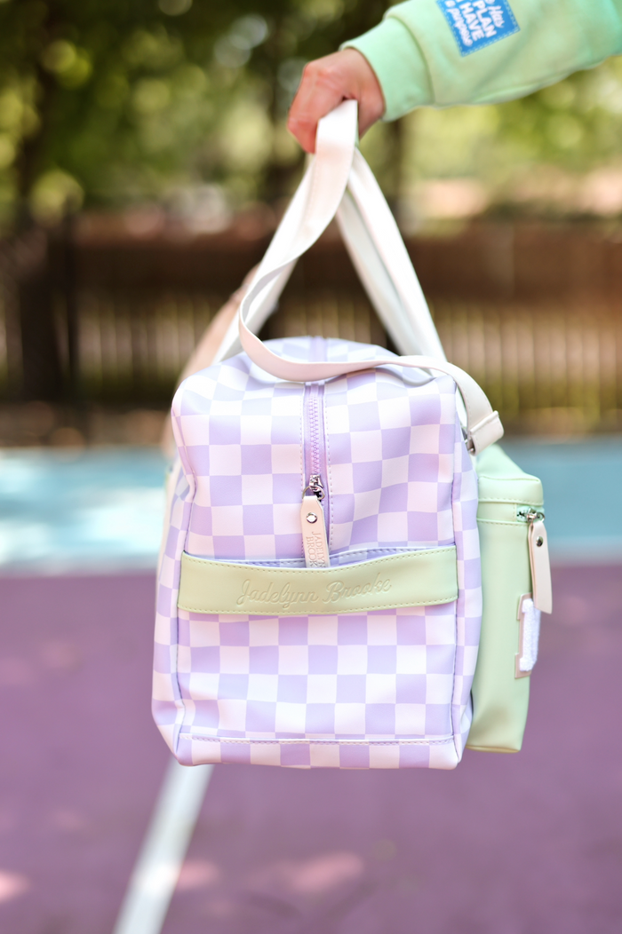 Purple and mint checkered duffel bag with strap, zippered closure, and logo by Jadelynn Brooke.