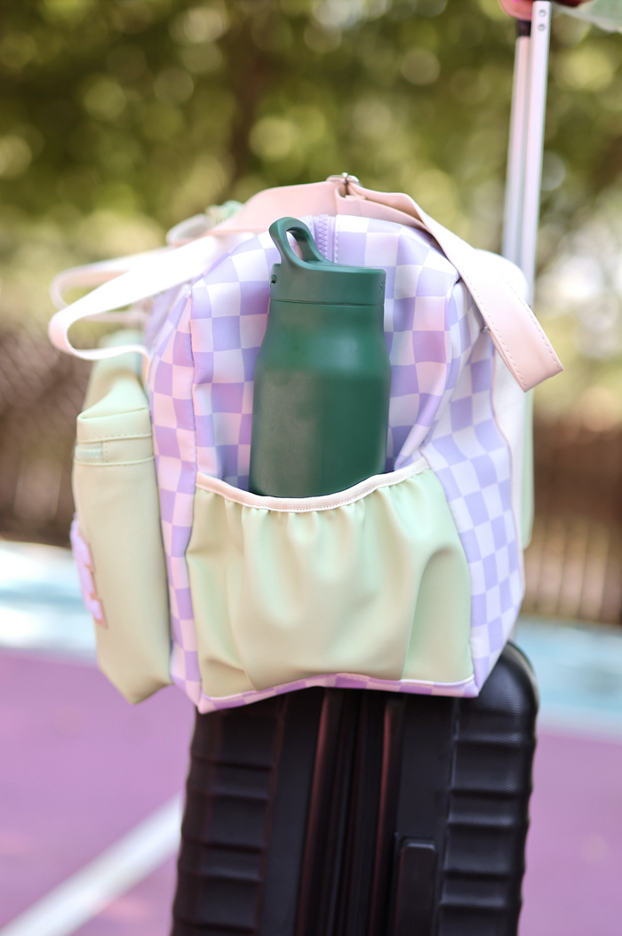Colorful checkered duffel bag in lavender and mint with side pocket for water bottle.