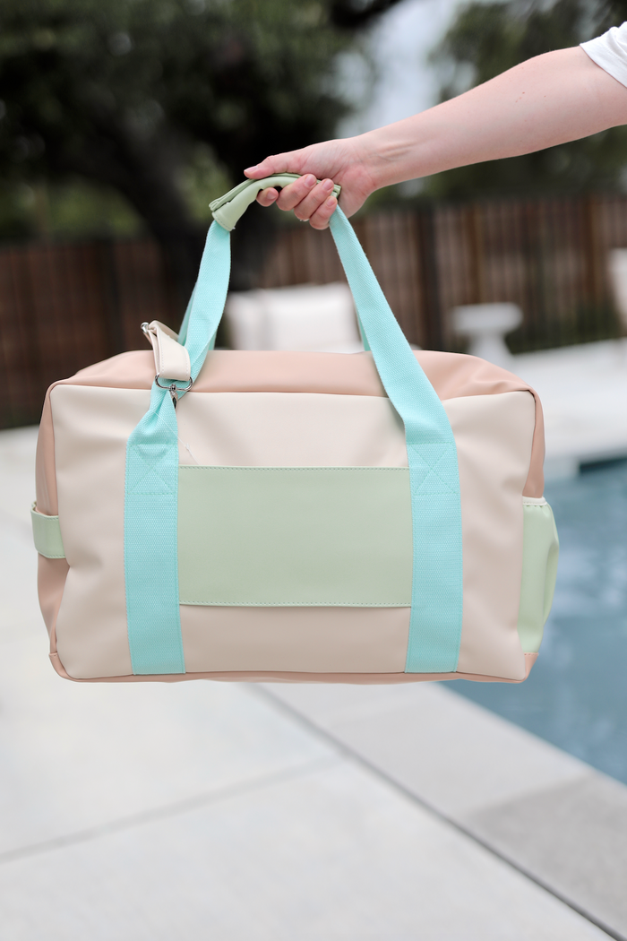 Stylish duffle bag in pastel peach and mint green, made from durable material, perfect for travel.