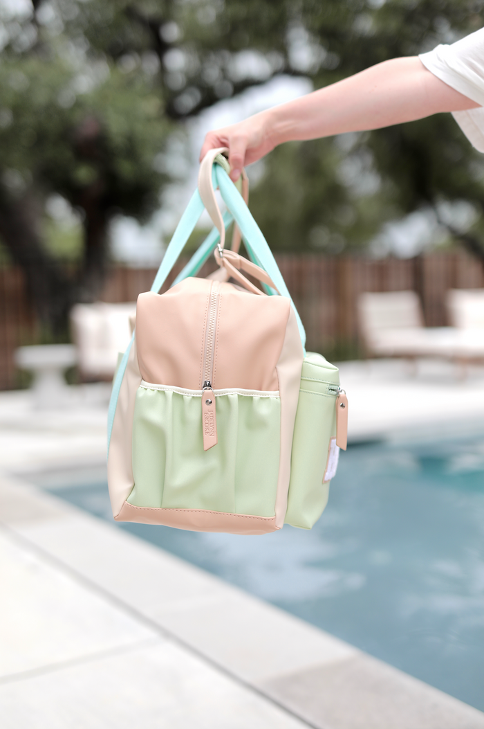 Stylish multi-colored tote bag in mint green and beige, featuring easy-access zip and exterior pockets.