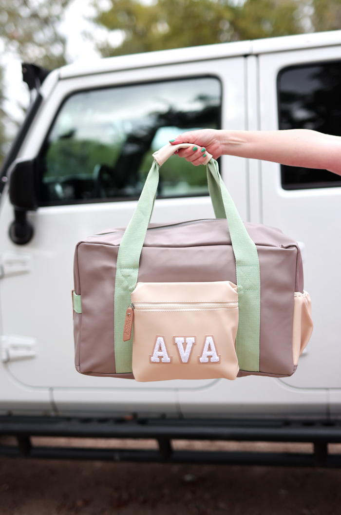 Stylish duffel bag in beige and green with personalized name patch, ideal for travel or gym.
