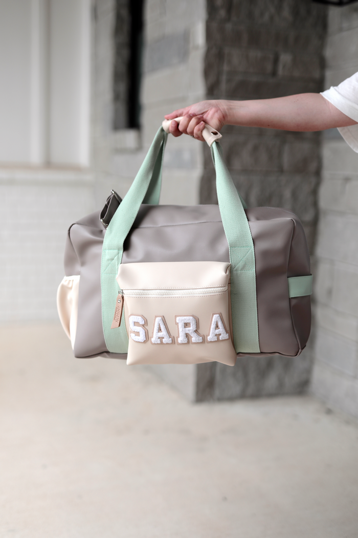 Stylish gray and mint duffel bag with personalized cream pouch, ideal for travel or gym.