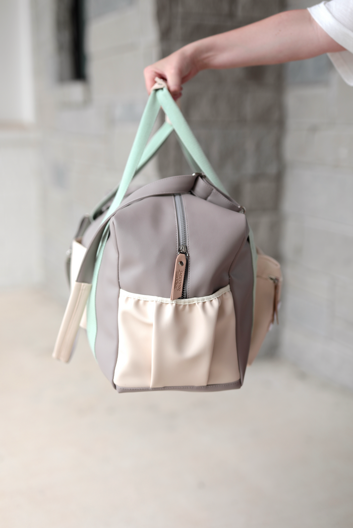 Stylish gray and beige duffle bag with mint green straps, perfect for gym and travel.