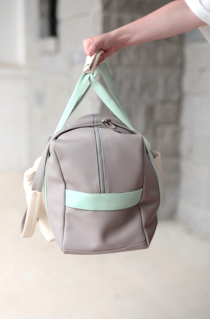 Stylish gray duffel bag with mint accents, made from durable material, perfect for travel or gym use.