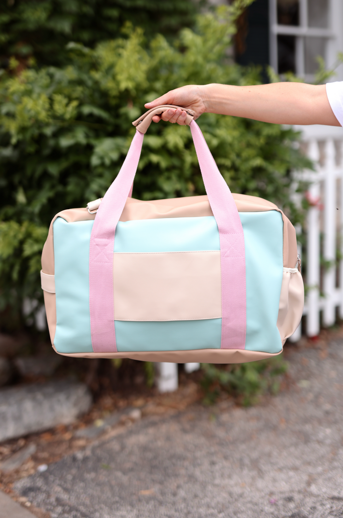 Stylish duffel bag in mint green and beige with pink straps, ideal for travel or gym.