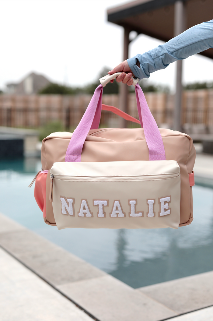 Stylish personalized pink and beige duffel bag with embroidered name, ideal for travel and sports.