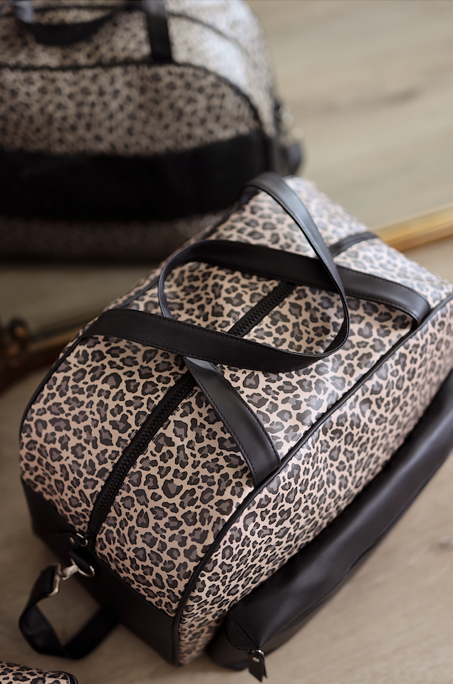 Stylish leopard print duffel bag with black leather accents, perfect for travel or gym use.