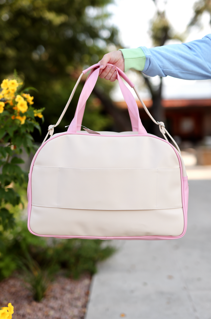 Stylish beige and pink duffel bag with dual handles, perfect for travel and everyday use.