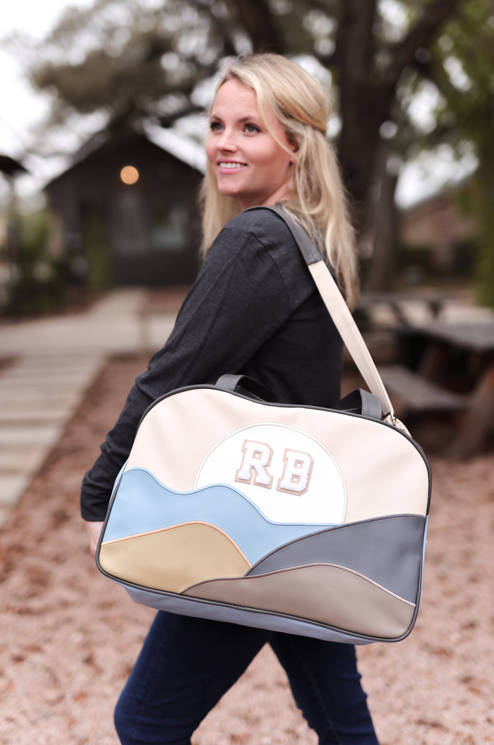 Stylish cream and blue tote bag with RB emblem, perfect for daily use or travel.