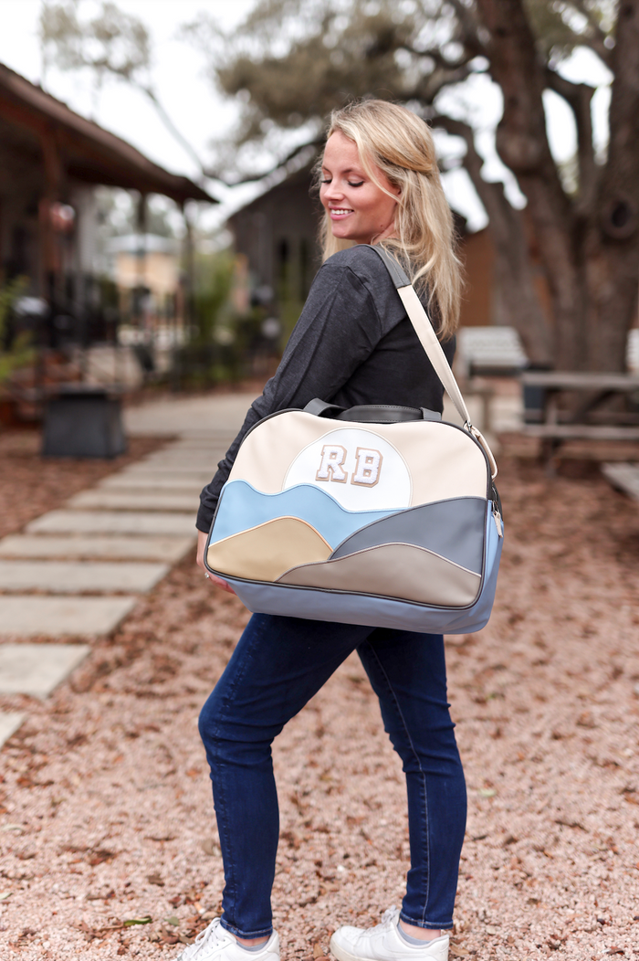 Stylish multicolored duffel bag in cream, blue, and gray, ideal for travel or gym.