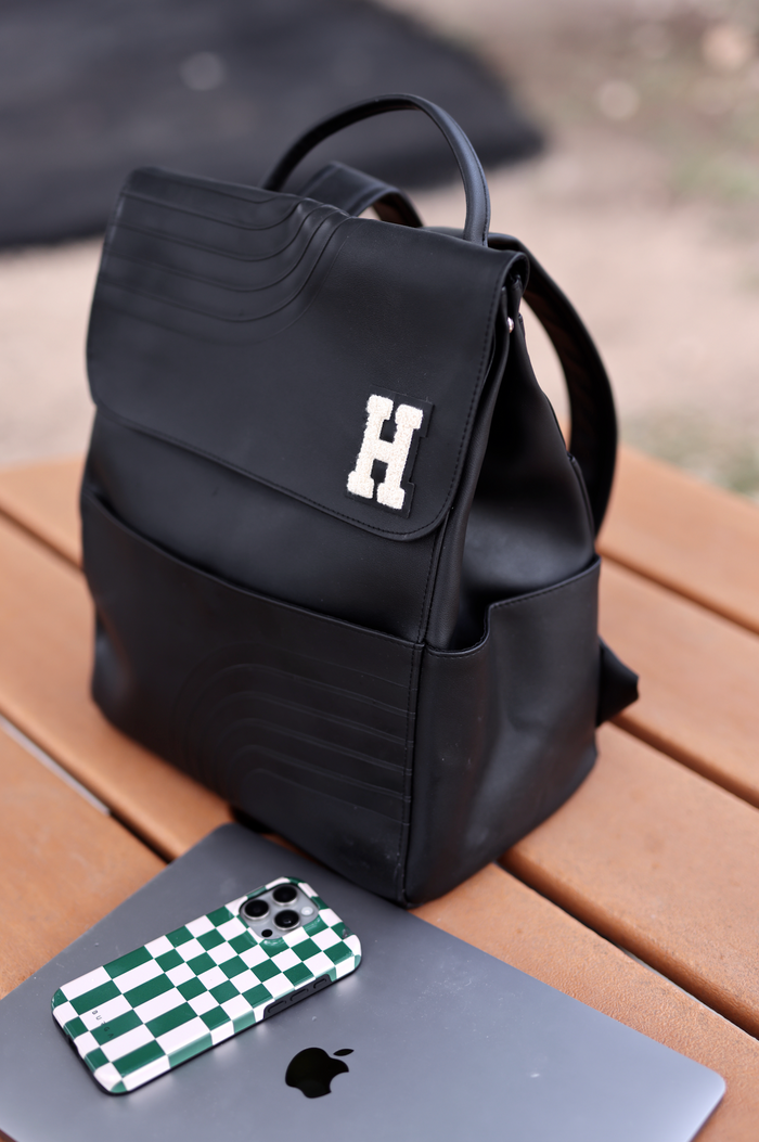 Stylish black backpack with textured detail and embroidered 'H' logo, perfect for everyday use.