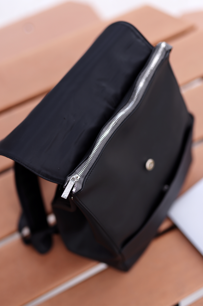Black vegan leather backpack with silver zipper and snap closure, perfect for everyday use.