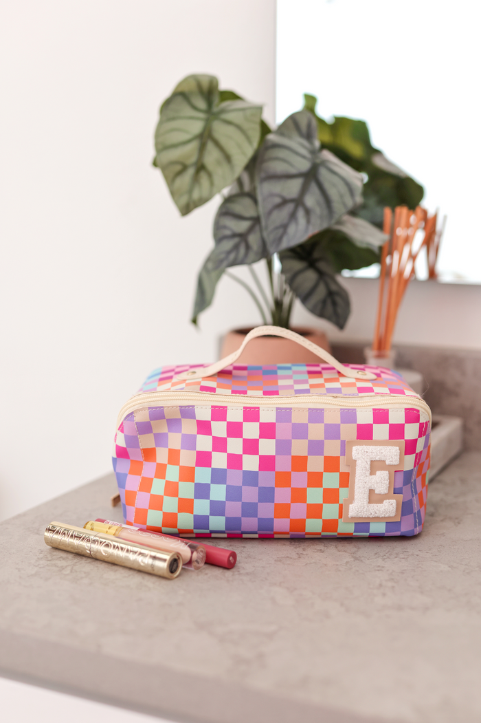 Colorful checked cosmetic bag with white E initial, perfect for makeup organization.