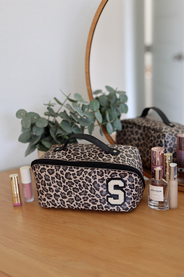Stylish leopard print makeup bag with handle and initial S, perfect for cosmetics storage.