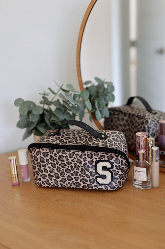 Stylish leopard print makeup bag with handle and initial S, perfect for cosmetics storage.