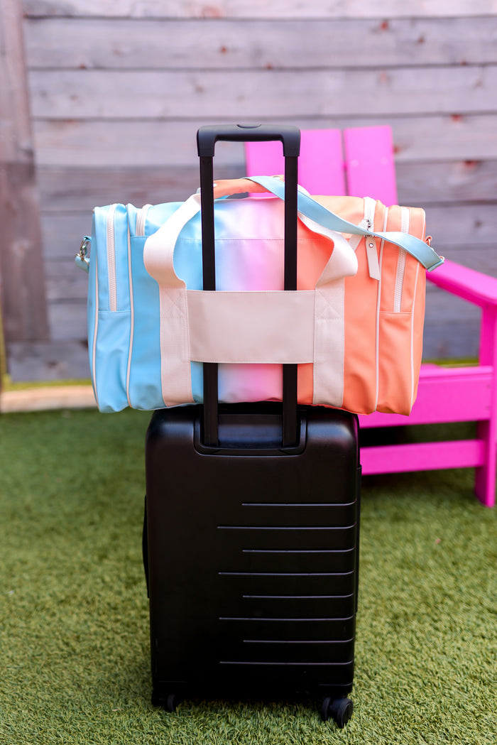 Black suitcase with colorful towels on a grassy area