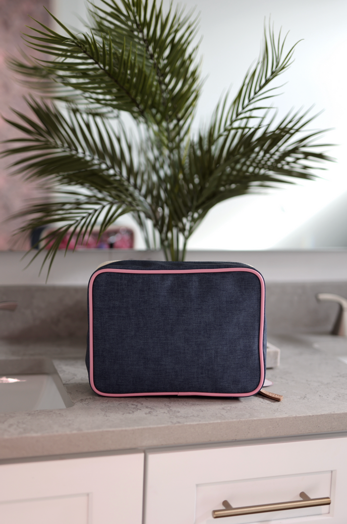 Navy blue travel toiletry bag with pink trim, durable fabric, perfect for organizing cosmetics and essentials.